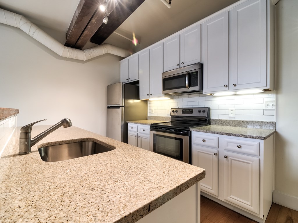A kitchen with a granite countertop and white cabinets.
