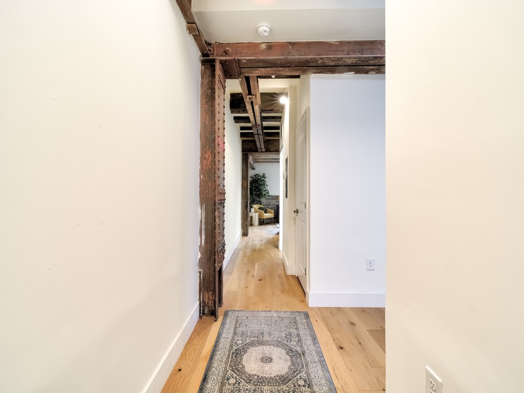 A hallway with a rug on the floor and a door on the right.