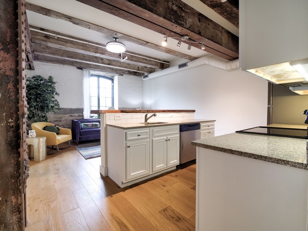 A kitchen with a white counter and a blue sofa in the background.