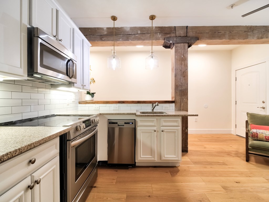 A kitchen with white cabinets and a wooden floor.