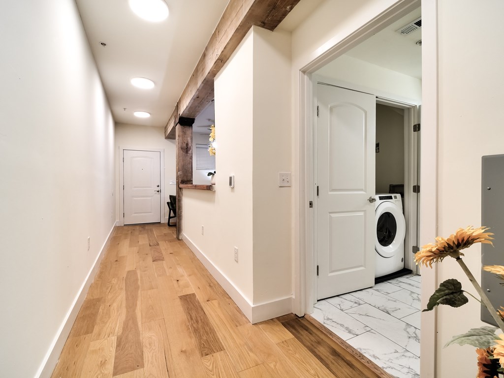 A hallway with a washing machine in the doorway.