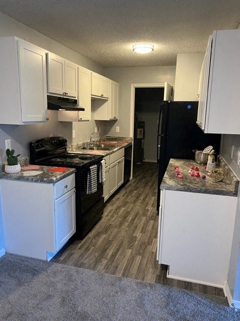 a kitchen with white cabinets and a black refrigerator