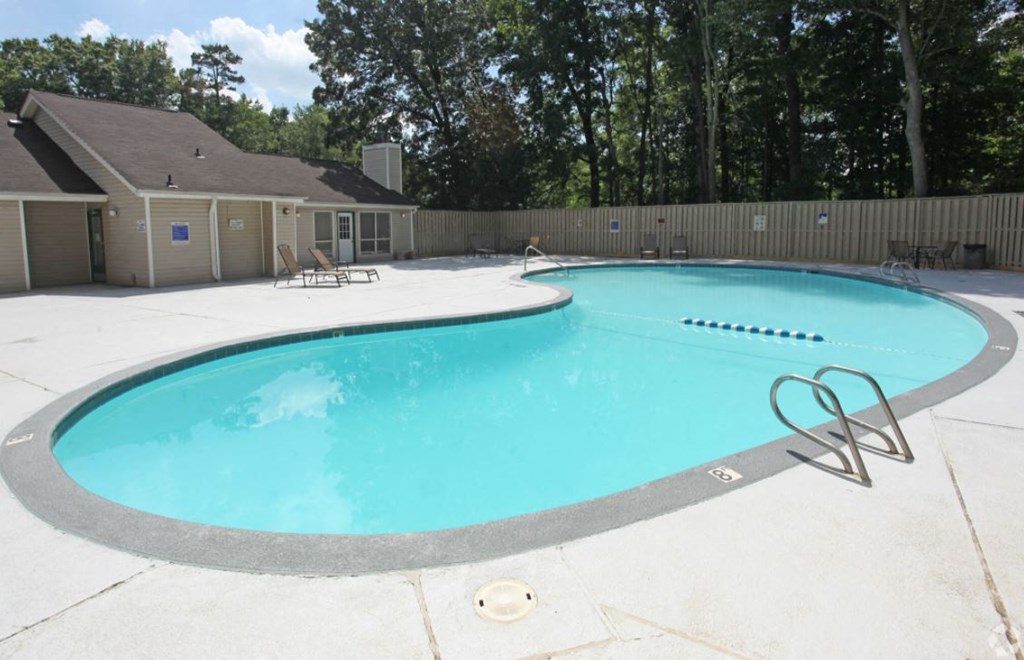 a resort style pool with chairs around it and a house in the background