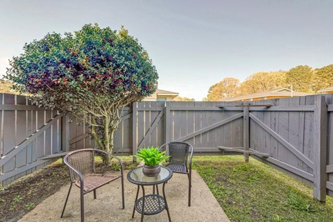 A backyard with a table and chairs and a tree.