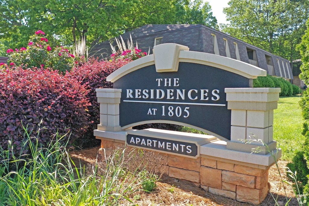 a sign for the residence at 1886 in front of a garden