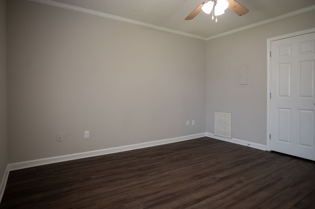 A room with a ceiling fan and wooden flooring.