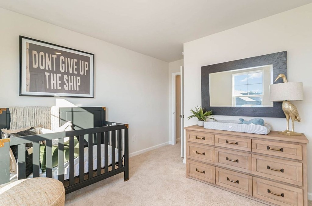 A nursery room with a crib, changing table, and a poster that says "Don't give up the ship".