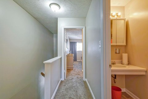A hallway with a white door on the left and a bathroom on the right.