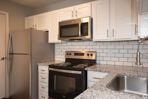 A kitchen with a stove, microwave, and refrigerator.