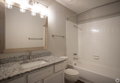 A bathroom with a granite countertop and white fixtures.