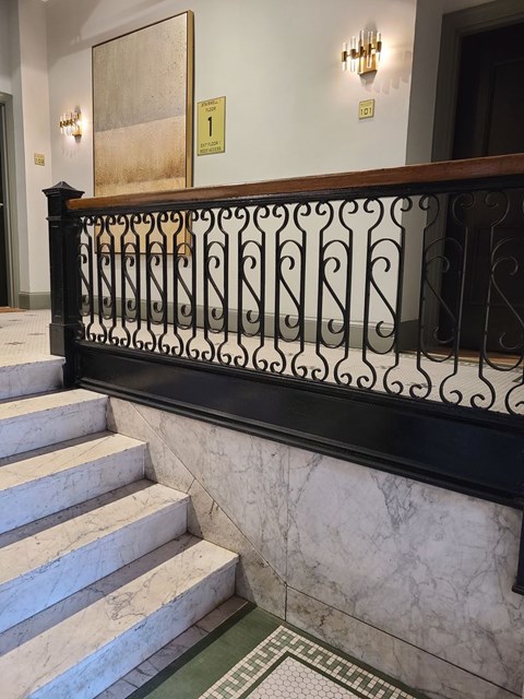 A staircase with a black railing and a marble floor.
