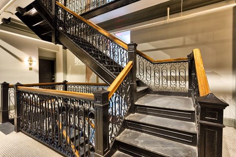 A staircase with a black metal railing and wooden steps.