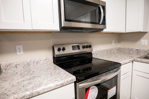A modern kitchen with a black stove top oven and white cabinets.