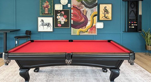 A pool table with a red cloth and white cue ball.