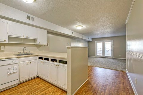 A kitchen with white cabinets and a wooden floor.
