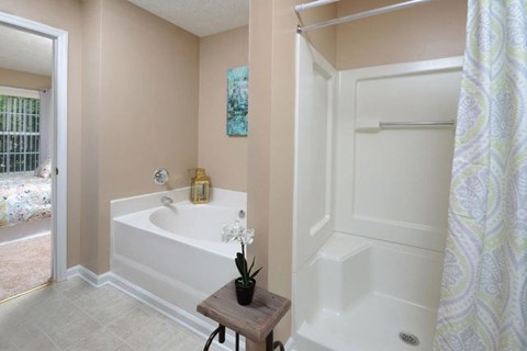 A bathroom with a white tub and a wooden stool.