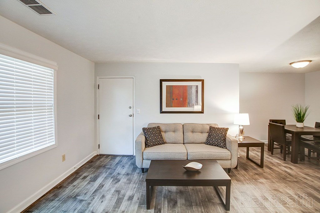 A living room with a couch, coffee table, and a painting on the wall.