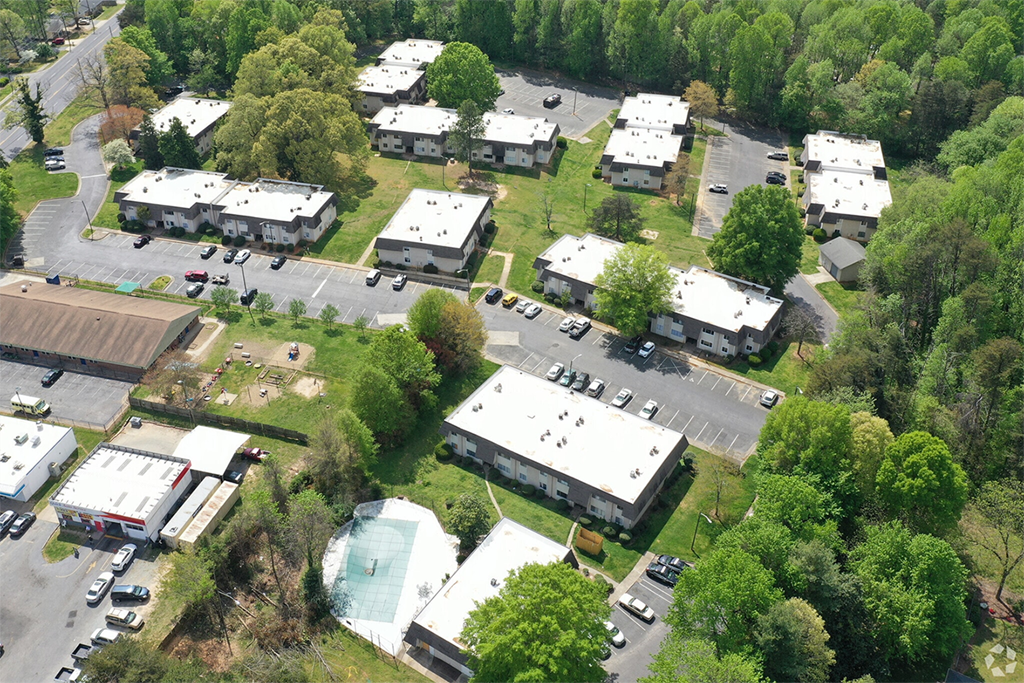 an aerial view of houses in a parking lot and trees