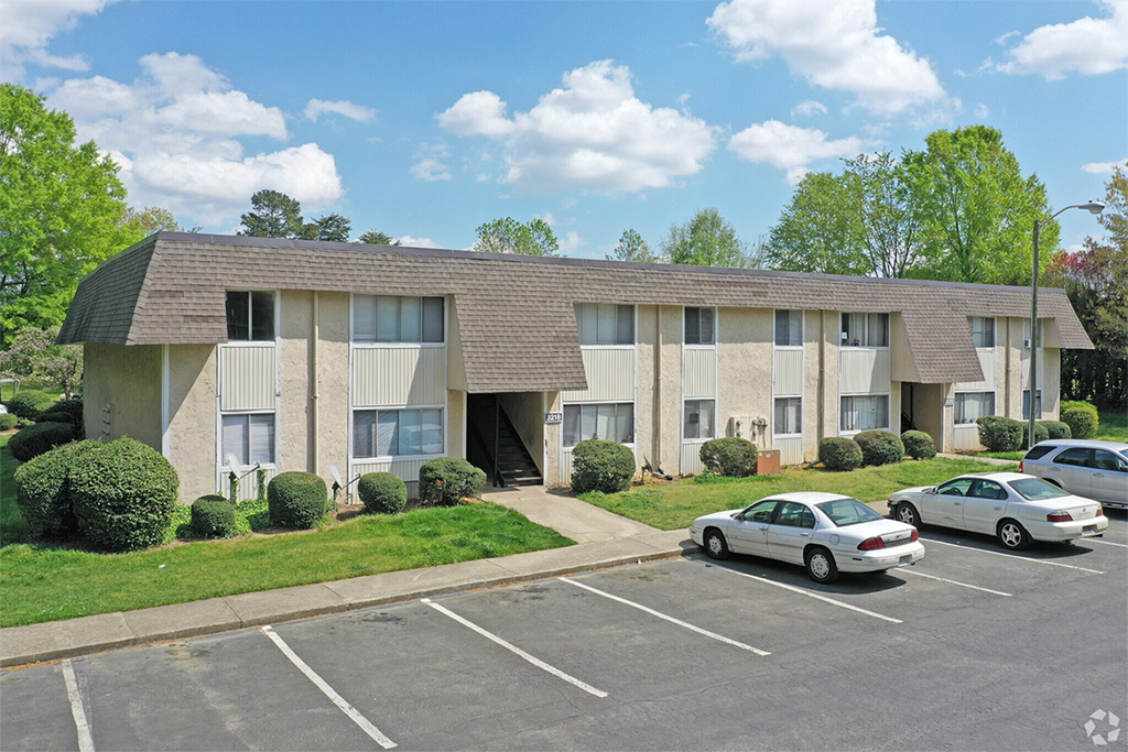 an apartment building in a parking lot with cars parked in front