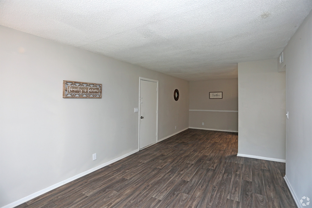 an empty living room with wood flooring and white walls