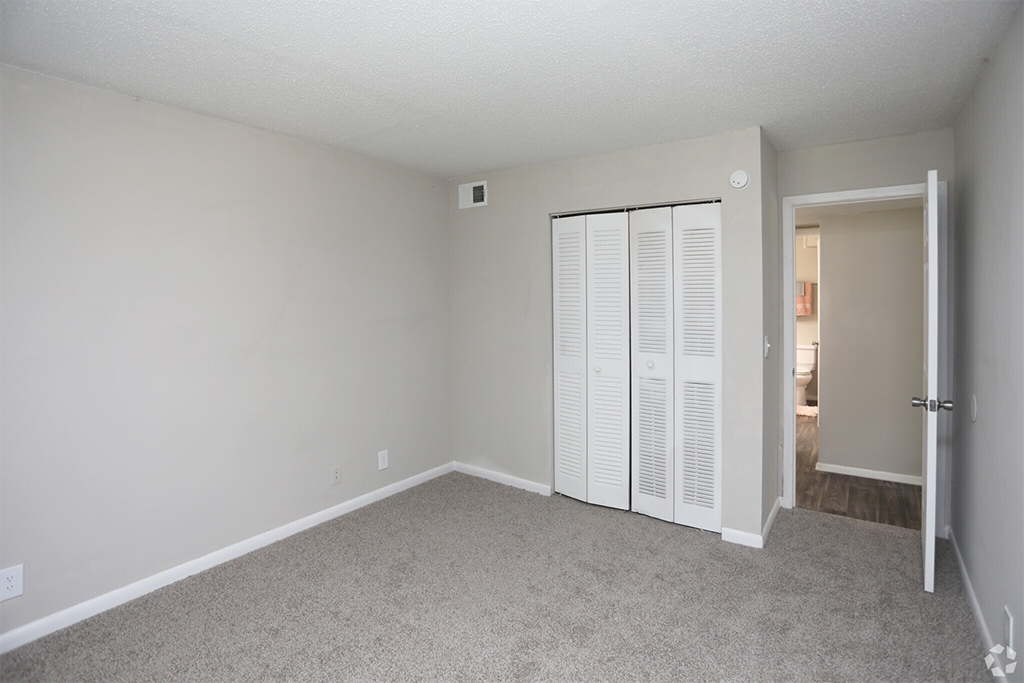 an empty bedroom with a closet and a door to a bathroom