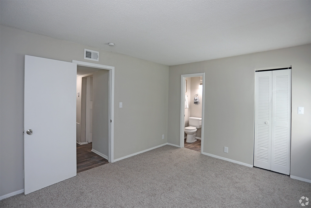 an empty living room with a door to a bathroom