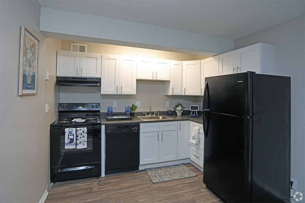 an empty kitchen with black appliances and white cabinets