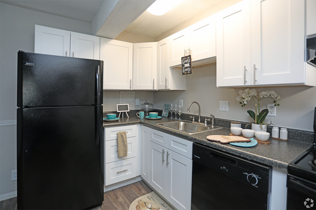 a kitchen with white cabinets and a black refrigerator