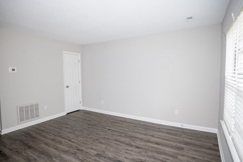 A room with a white door and a window with blinds.