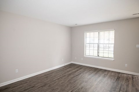 A room with a window and wooden flooring.