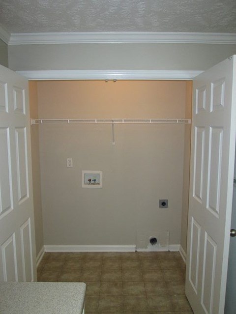 A room with a white door and a brown carpet.