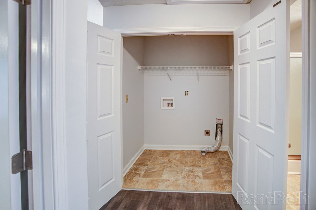 A white closet with a tile floor and a white door.