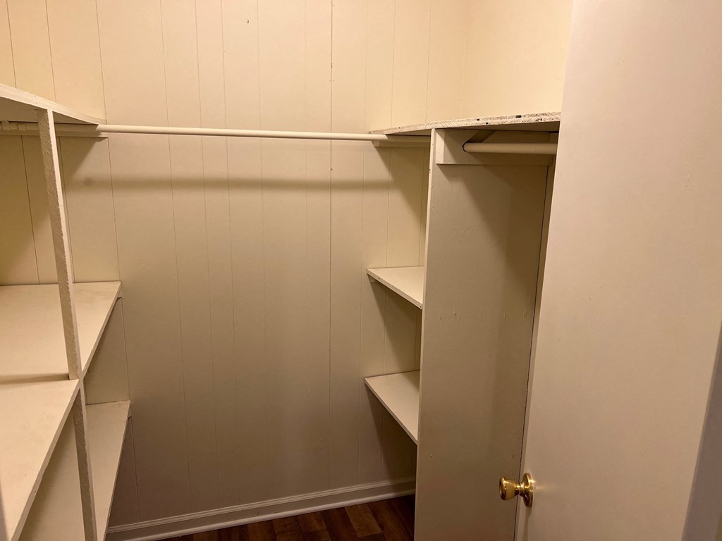 a walk in closet with white shelves and a door