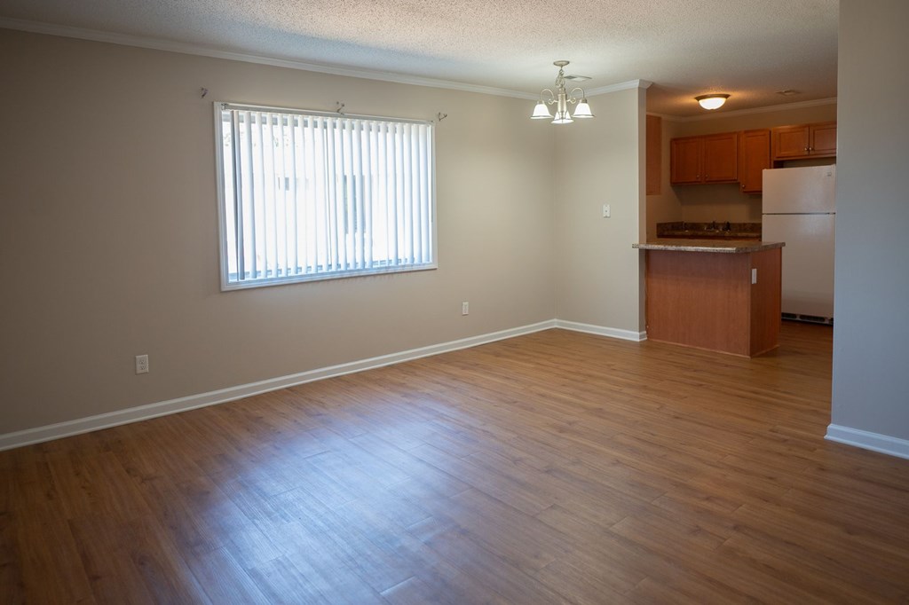 A room with wooden floors and a window with blinds.