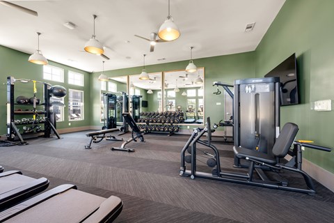 A gym with a variety of equipment including treadmills, weights, and exercise machines.