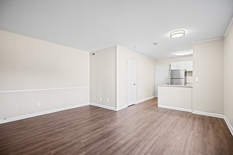 A room with wood flooring and a refrigerator.