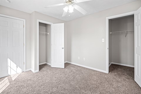 A room with a carpeted floor and a ceiling fan.