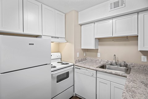 A white kitchen with a refrigerator, stove, and sink.