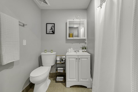 A white bathroom with a toilet, sink, and shower curtain.