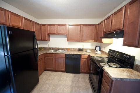 A kitchen with brown cabinets and black appliances.