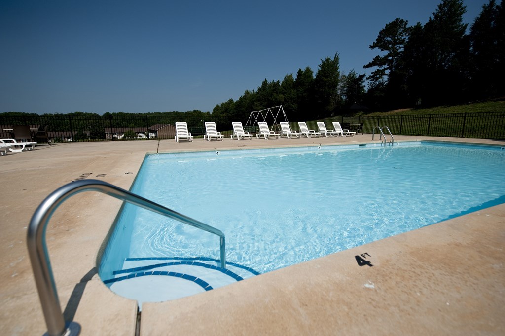 A pool with a ladder and chairs around it.