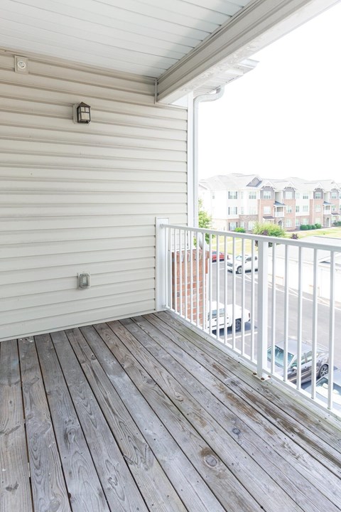 A balcony with a white railing and wooden floor.