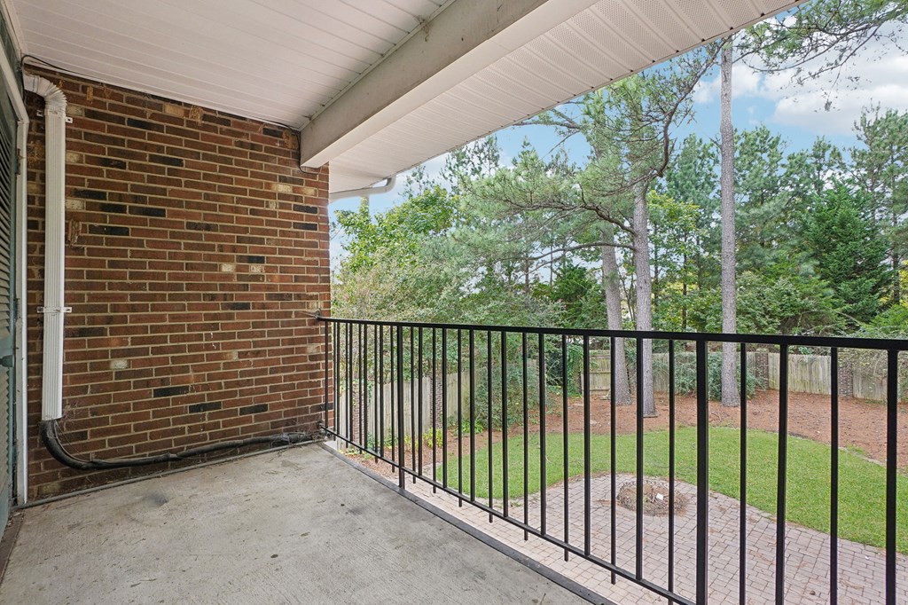 A balcony with a black railing and a brick wall.