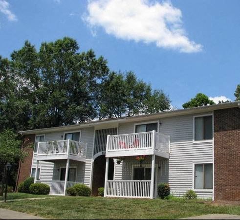 a white apartment building with balconies and trees