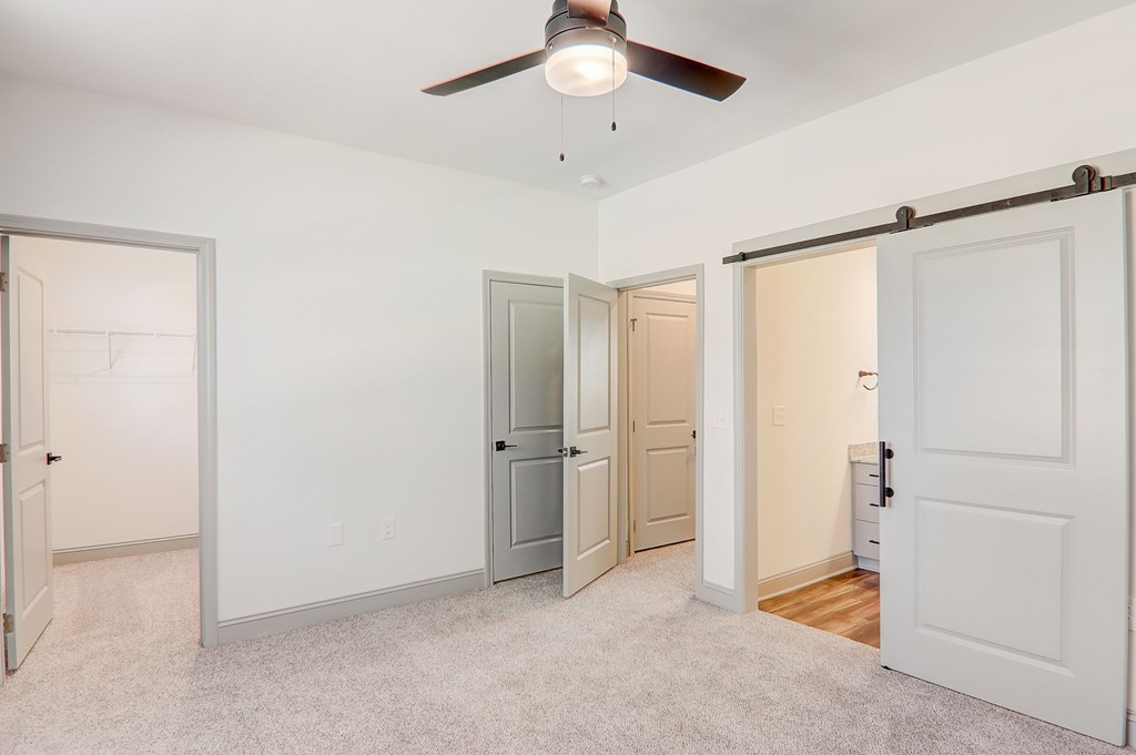 A room with a ceiling fan and three doors.
