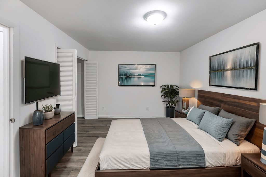 A bedroom with a large bed and a television on a cabinet.
