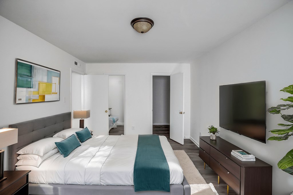 A bedroom with a large bed and a flat screen TV mounted on the wall.