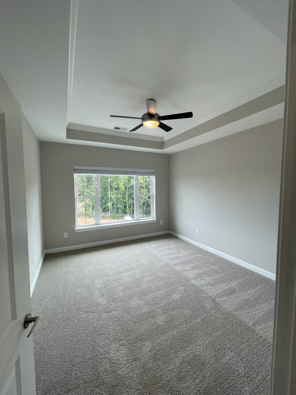 an empty living room with a ceiling fan and a window