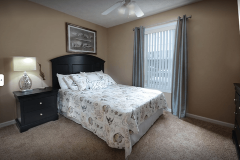 A bedroom with a bed, nightstand, and a ceiling fan.