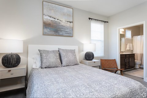 A bedroom with a large bed and a painting on the wall.